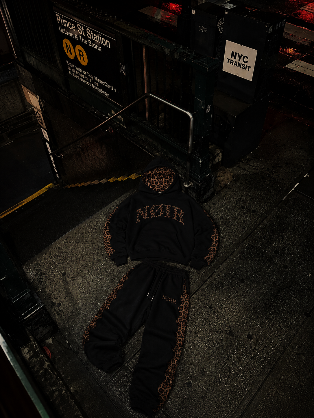 NØIR THE ICON tracksuit laid out on a wet New York sidewalk at night